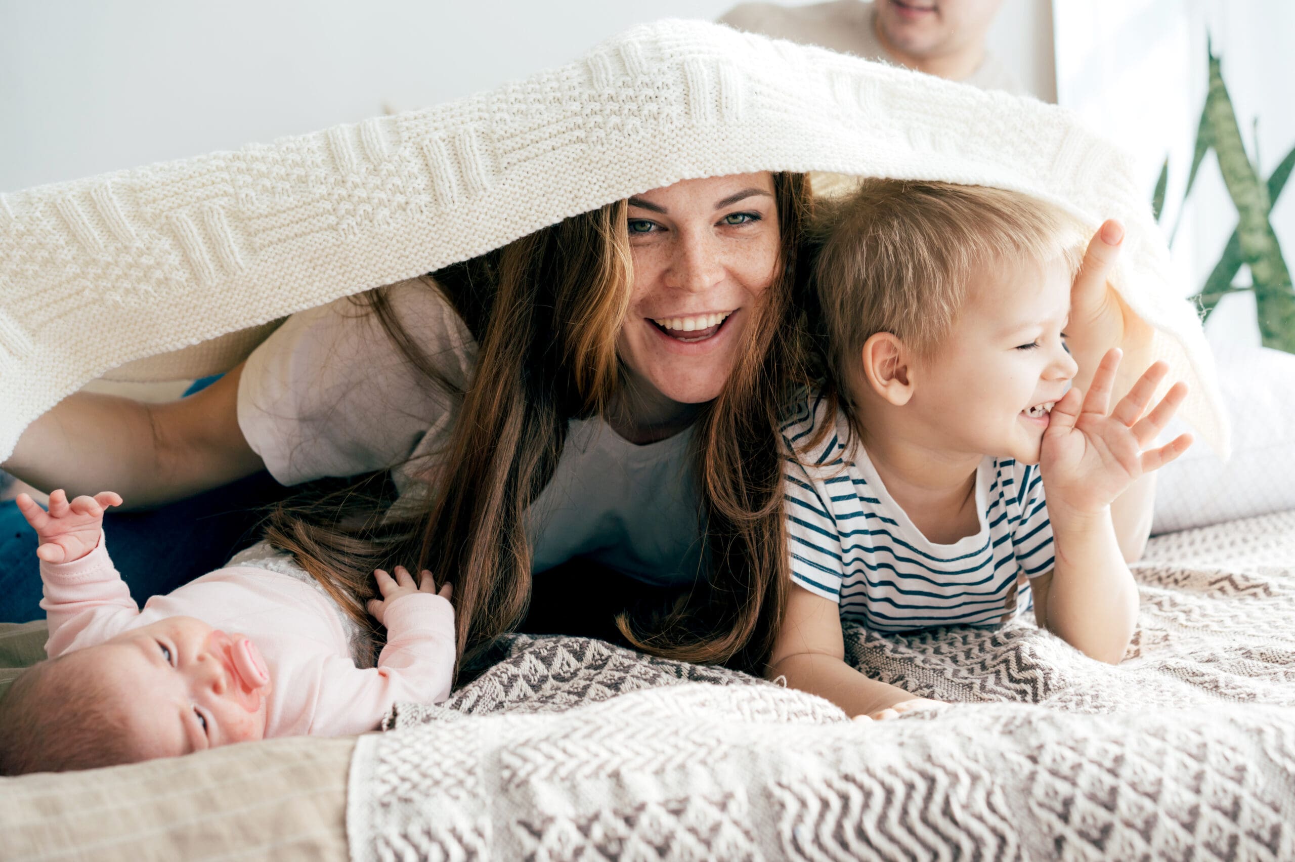 happy-mommy-plays-with-the-children-on-the-bed-and-2023-11-27-05-18-35-utc-scaled-min