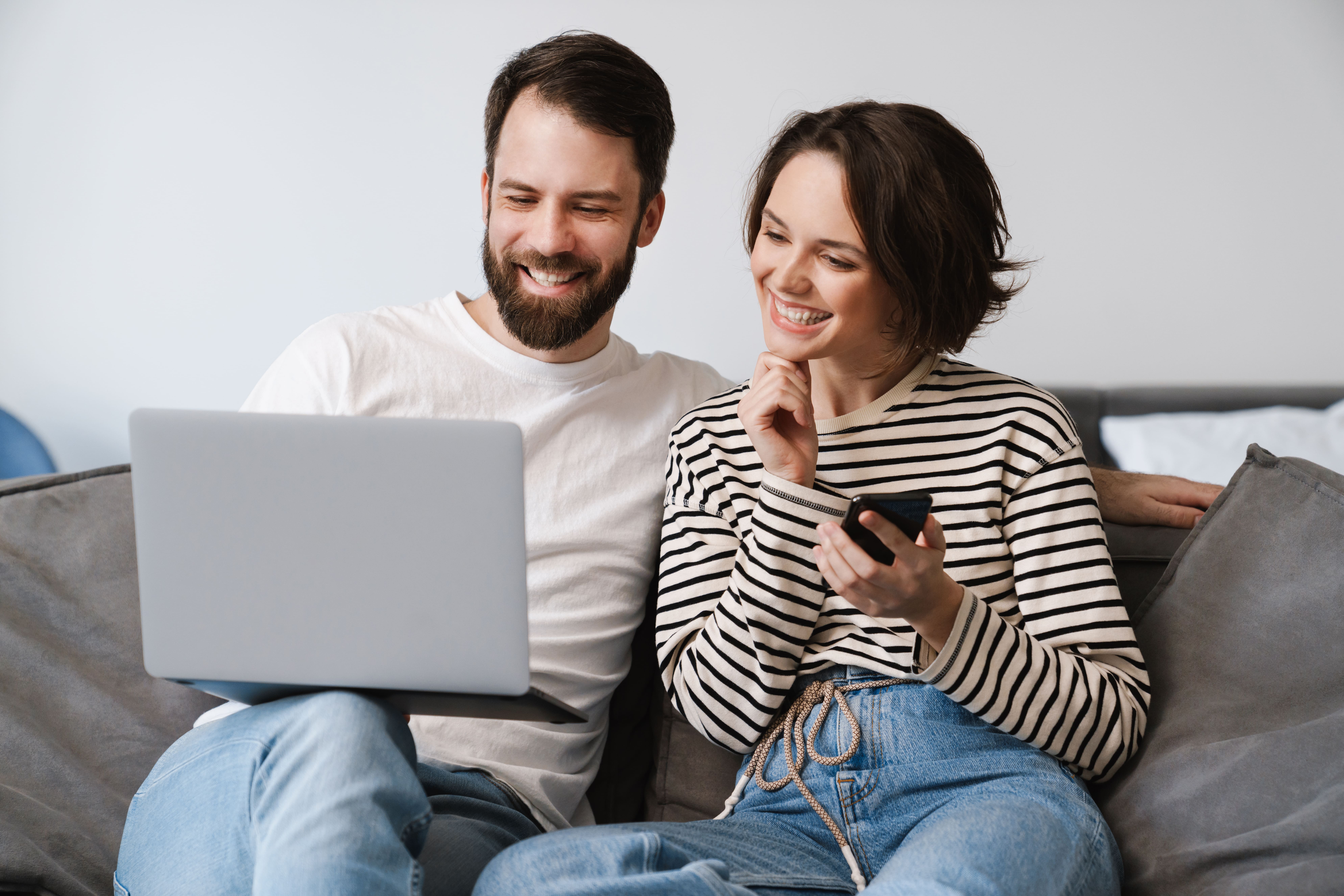 happy-young-white-couple-sitting-on-a-couch-at-hom-2023-11-27-05-03-17-utc (1)-min